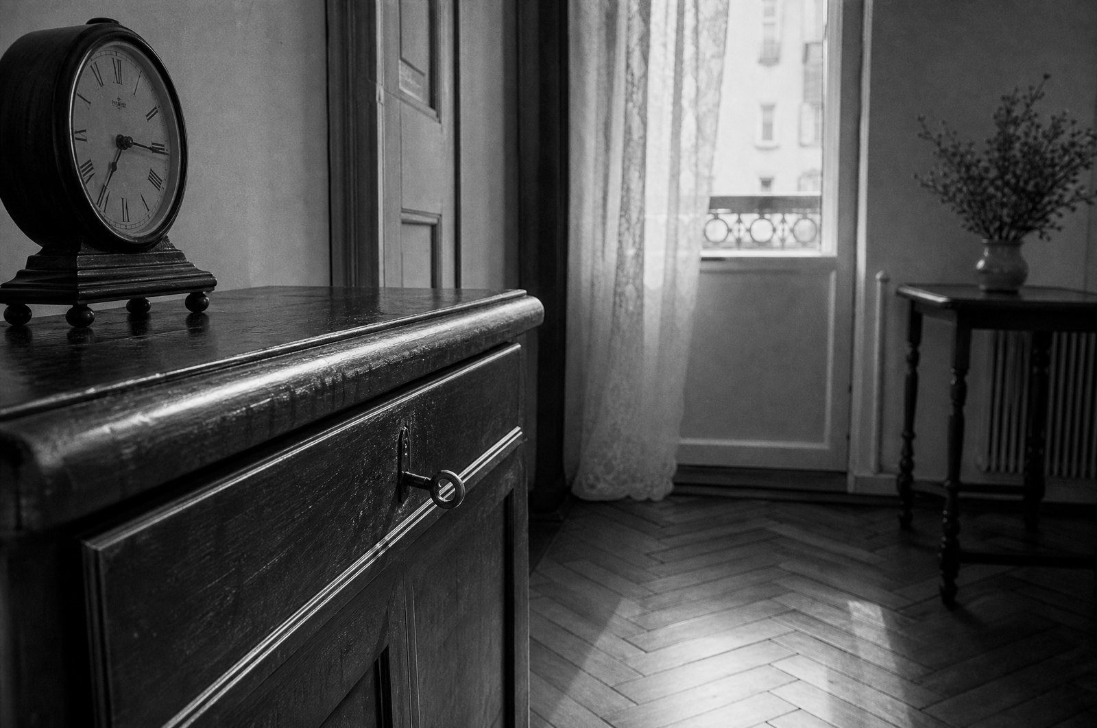 Pokój w starym mieszkaniu: zegar na drewnianej komodzie, parkiet w jodełkę i okno z firanką